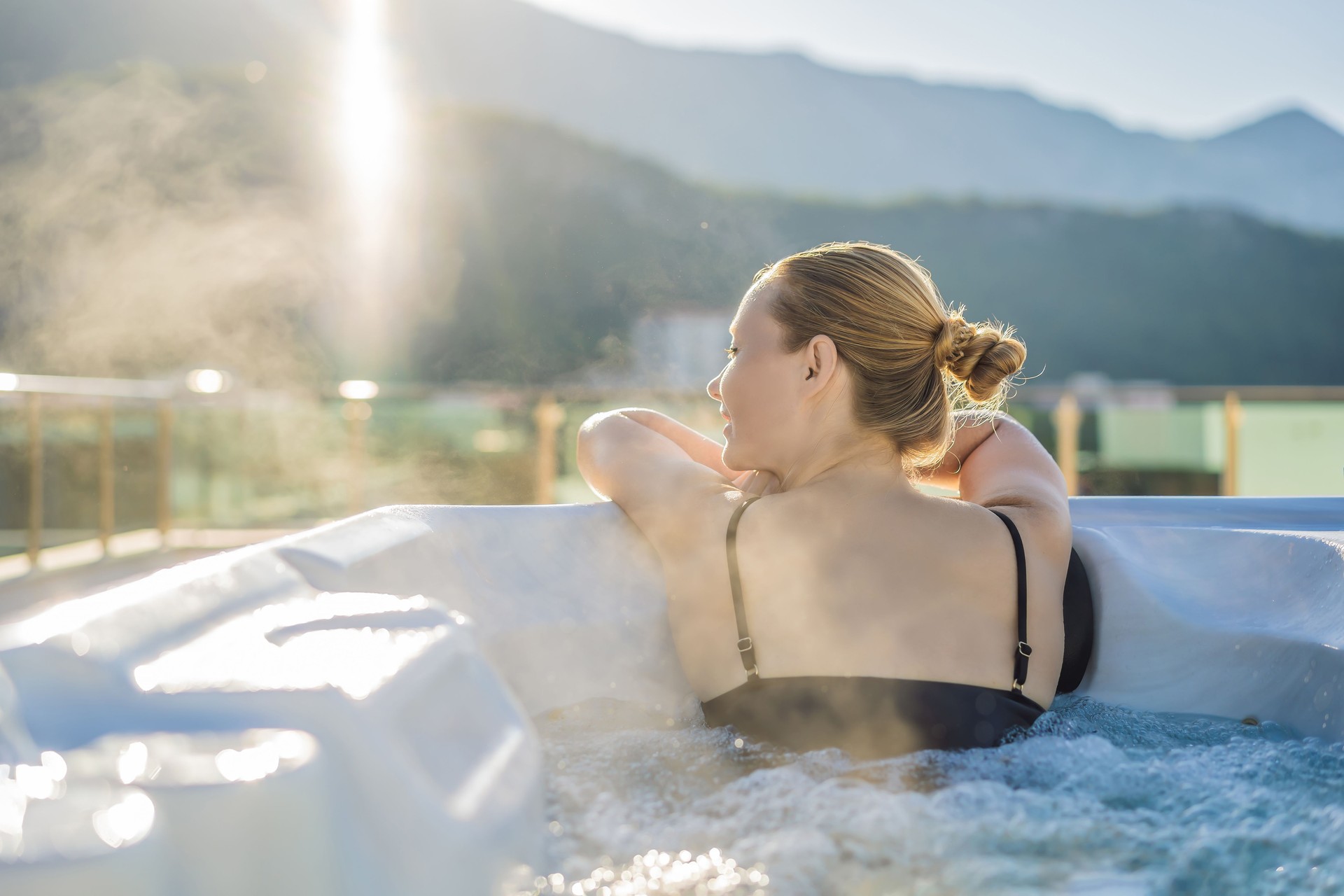 Portrait of young carefree happy smiling woman relaxing at hot tub during enjoying happy traveling moment vacation life against the background of green big mountains