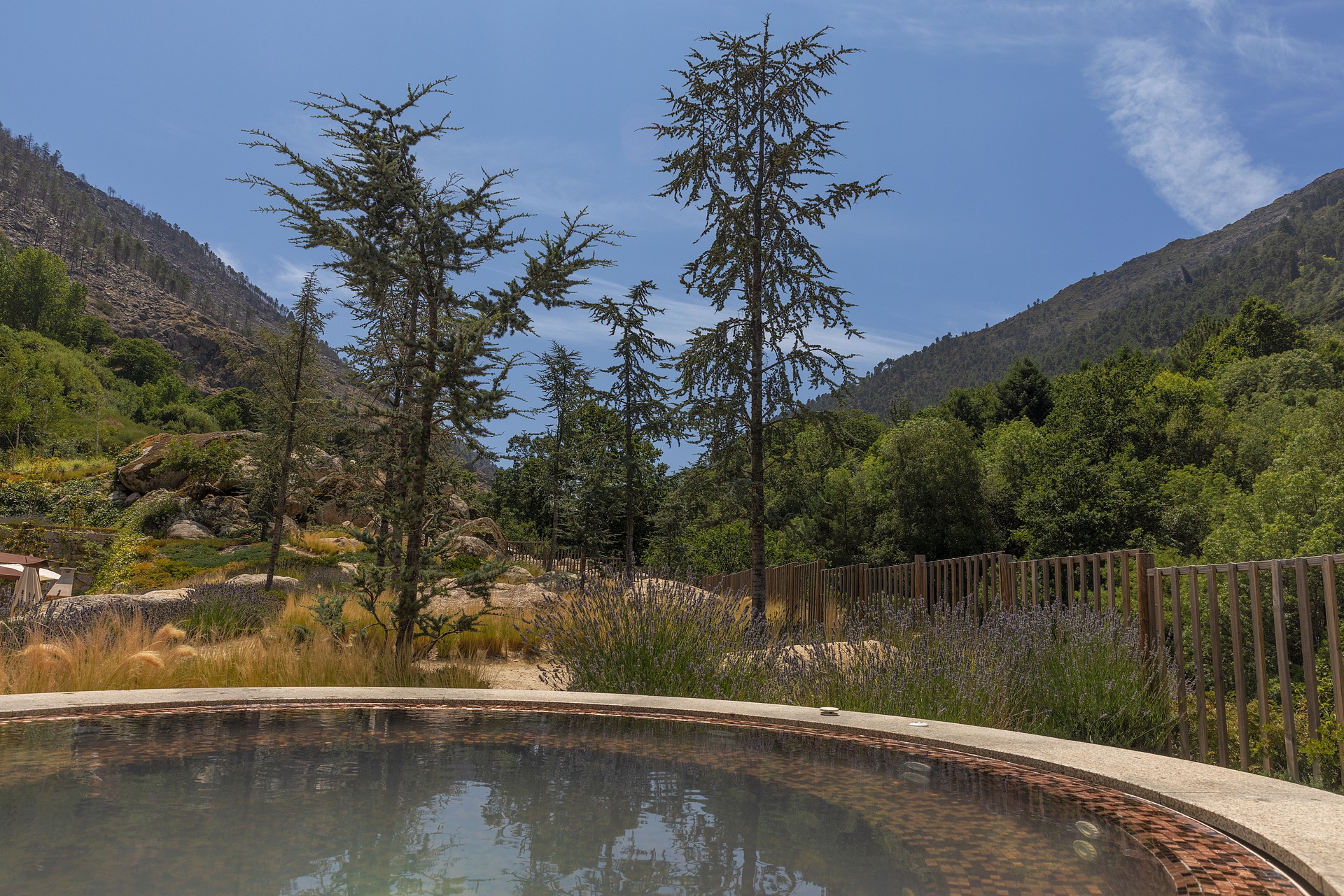 hot water hot tub set in a natural environment with mountains and vegetation.